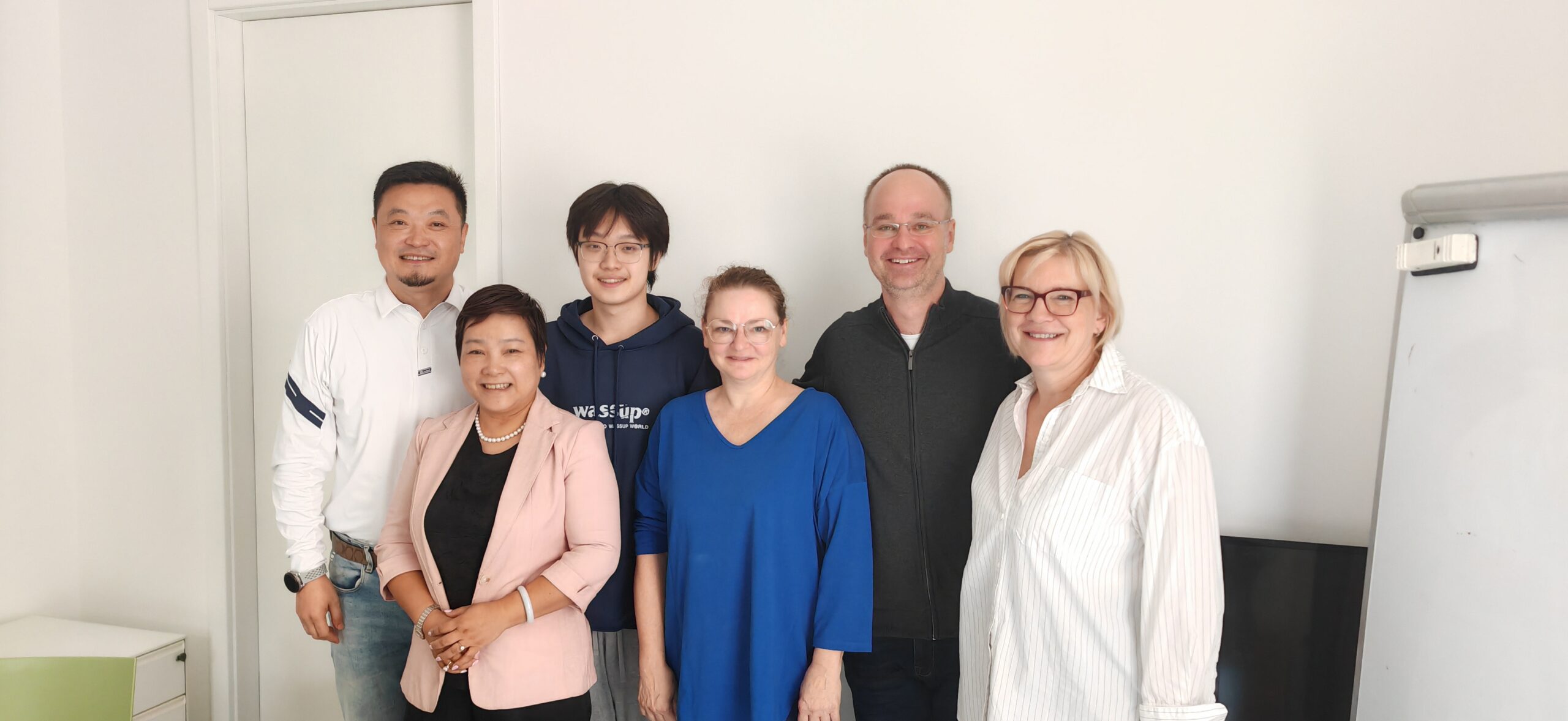 Student and adults gathering for a group photograph indoors